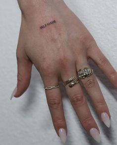 a woman's hand with three different rings on her left wrist and the word self made written in black ink