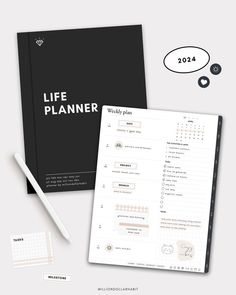 a black and white life planner next to a pen, pencil and paper on a table