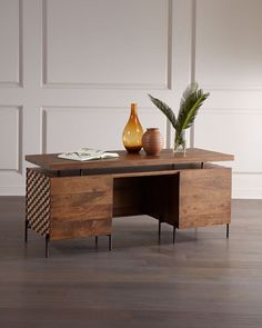 a wooden table with two vases on it and a plant in the corner next to it