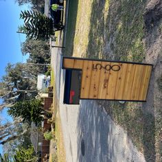 a wooden sign sitting on the side of a road next to a grass covered field