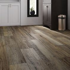 a kitchen with white cabinets and wood floors is shown in this image, there is a trash can on the floor