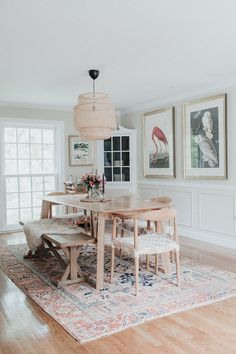 a dining room table and chairs with pictures on the wall above it, along with an area rug