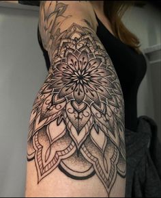 a woman's arm with an intricate tattoo design on the back of her shoulder