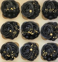 twelve cupcakes with black frosting and gold sprinkles