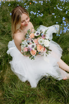 A Bride Holding A Bouquet Of Flowers Smiling On A Field.