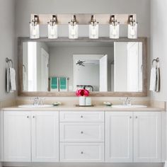 a bathroom with two sinks, mirrors and lights on the wall above them is shown