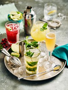 several glasses of different kinds of drinks on a silver tray