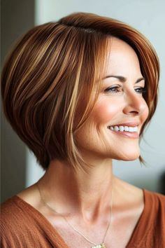 Highlighted Layered Bob Hairstyle on a smiling woman in her 50s with short golden brown hair, side view.