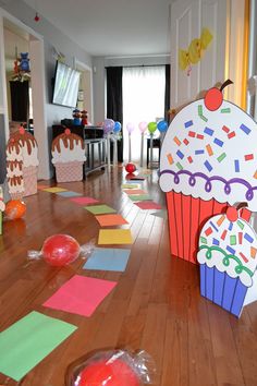 an open room with lots of colorful paper cut outs on the floor and decorated cupcakes