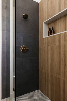 a bathroom with a walk in shower next to a tiled floor and wooden paneled walls