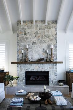 a living room with a stone fireplace and two candles on the mantel above it