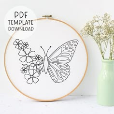 a cross stitch pattern with a butterfly and flowers in the hoop next to a vase filled with baby's breath