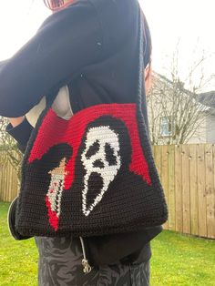 a woman is holding a crocheted bag in the shape of a pirate ship