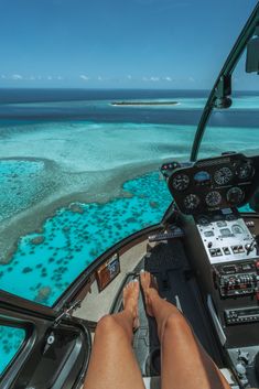 a person sitting in the cockpit of a plane flying over water and corals on land