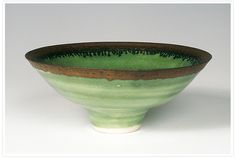 a green and brown bowl sitting on top of a white table