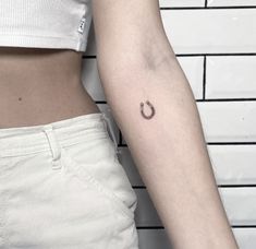 a woman's left arm with a small horseshoe tattoo on the right side of her body