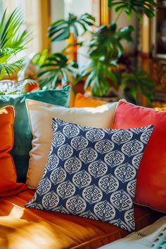 a bunch of pillows sitting on top of a couch in front of a potted plant