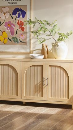 a wooden sideboard with two vases on top of it and a painting behind it