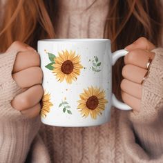 a woman holding a coffee mug with sunflowers painted on it