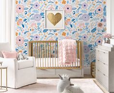 a baby's room decorated in pink, blue and gold with floral wallpaper