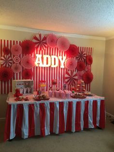 a candy bar with red and white striped paper decorations on the wall behind it is an ady sign