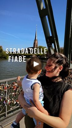 a woman holding a small child on top of a bridge with the words straddlele