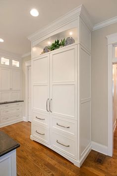 a kitchen with white cabinets and wood floors