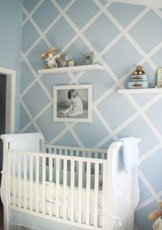 a baby's room decorated in blue and white with shelves above the crib