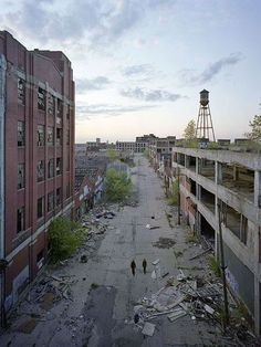 an old run down city street with lots of debris on the ground and water tower in the distance