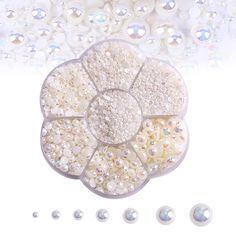 white pearls and crystal stones arranged in the shape of a flower on a white background