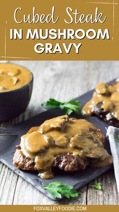 two steaks covered in mushroom gravy on top of a black slate plate