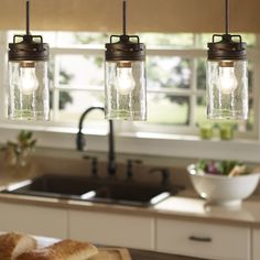 three mason jar lights hanging over a kitchen counter with croissants on it