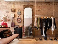 a clothing store with clothes hanging on racks, and a couch in the foreground