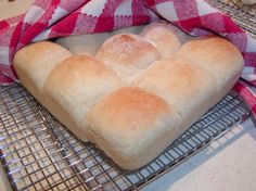 a loaf of bread sitting on top of a cooling rack next to a red and white checkered towel