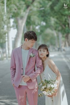 a young man and woman standing next to each other on the side of a road