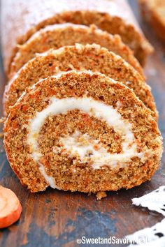 carrot roll with cream cheese frosting and sliced carrots next to it on a cutting board