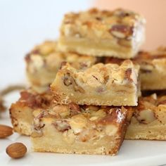 several pieces of dessert sitting on top of a white plate with almonds around it