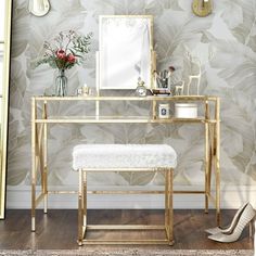 a dressing table with a mirror, stool and flowers on the wall next to it