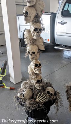 a bunch of fake skulls are stacked on top of each other in a parking garage