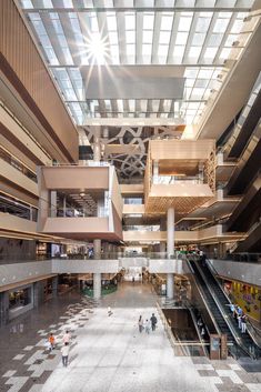 an indoor shopping mall with escalators, stairs and people walking through the area