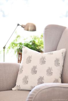 a white pillow sitting on top of a gray couch next to a green potted plant