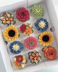 the cupcakes in the box are decorated with flowers