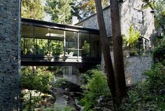 the house is surrounded by greenery and stone walls, along with an outdoor deck