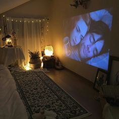 a room with a large screen on the wall next to a rug and lights in front of it