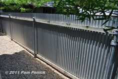 a metal fence is shown with gravel in the foreground