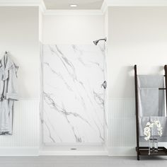 a bathroom with white walls and marble tile on the shower wall, along with towel racks