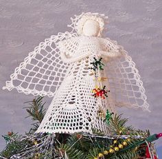 a crocheted angel sitting on top of a christmas tree