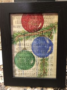 a framed art piece with christmas ornaments hanging from it