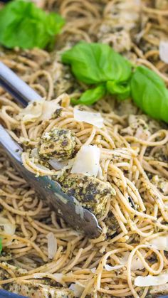 pasta with pesto and parmesan cheese in a blue bowl next to basil leaves