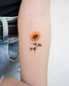 a small sunflower tattoo on the left arm